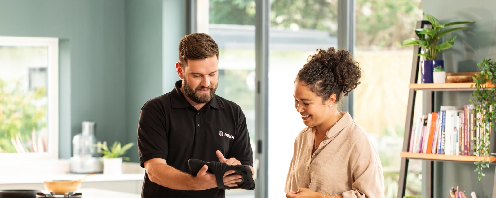 Eine Frau und ein Installateur Bosch stehen in einer Küche und unterhalten sich.