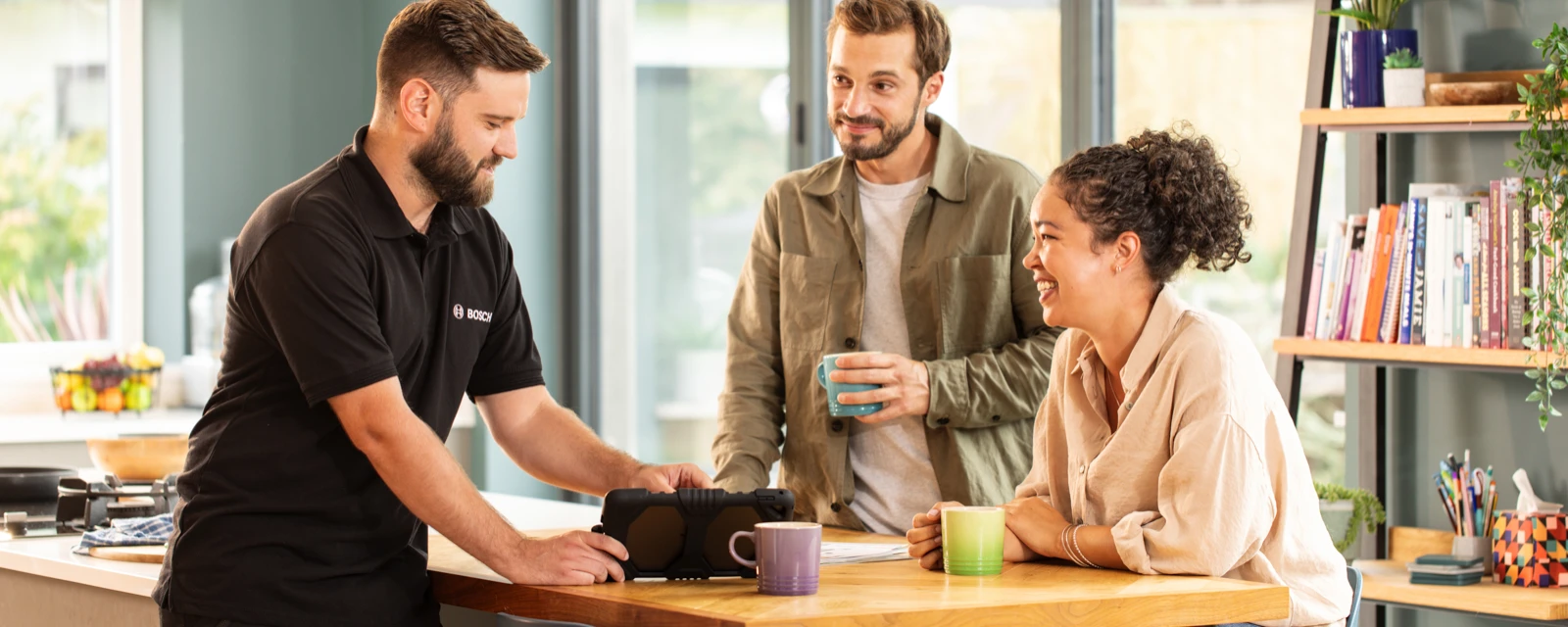 Paar unterhält sich mit Installateur in der Küche.