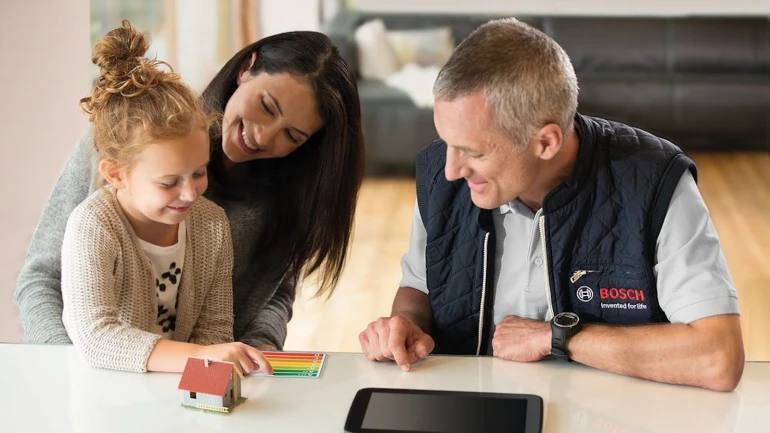 Ein Installateur sitzt mit jungen Familie am Tisch.