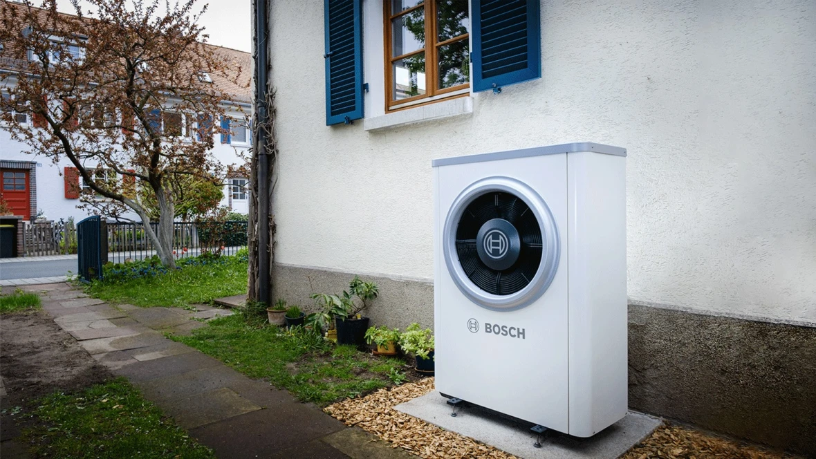 Eine Wärmepumpe 7400i AW von Bosch steht vor der Hauswand eines Altbaus.