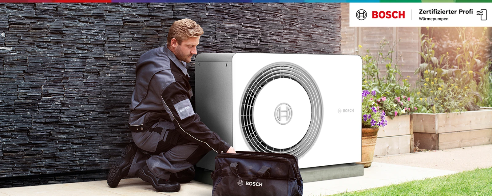 Monteur sitzt neben einer Wärmepumpe im Garten und greift in seine Tasche.
