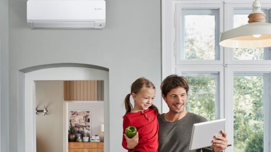 Familie steht im Wohnzimmer, in welchem eine Klimaanlage angebracht ist Familie steht im Wohnzimmer, in welchem eine Klimaanlage angebracht ist
