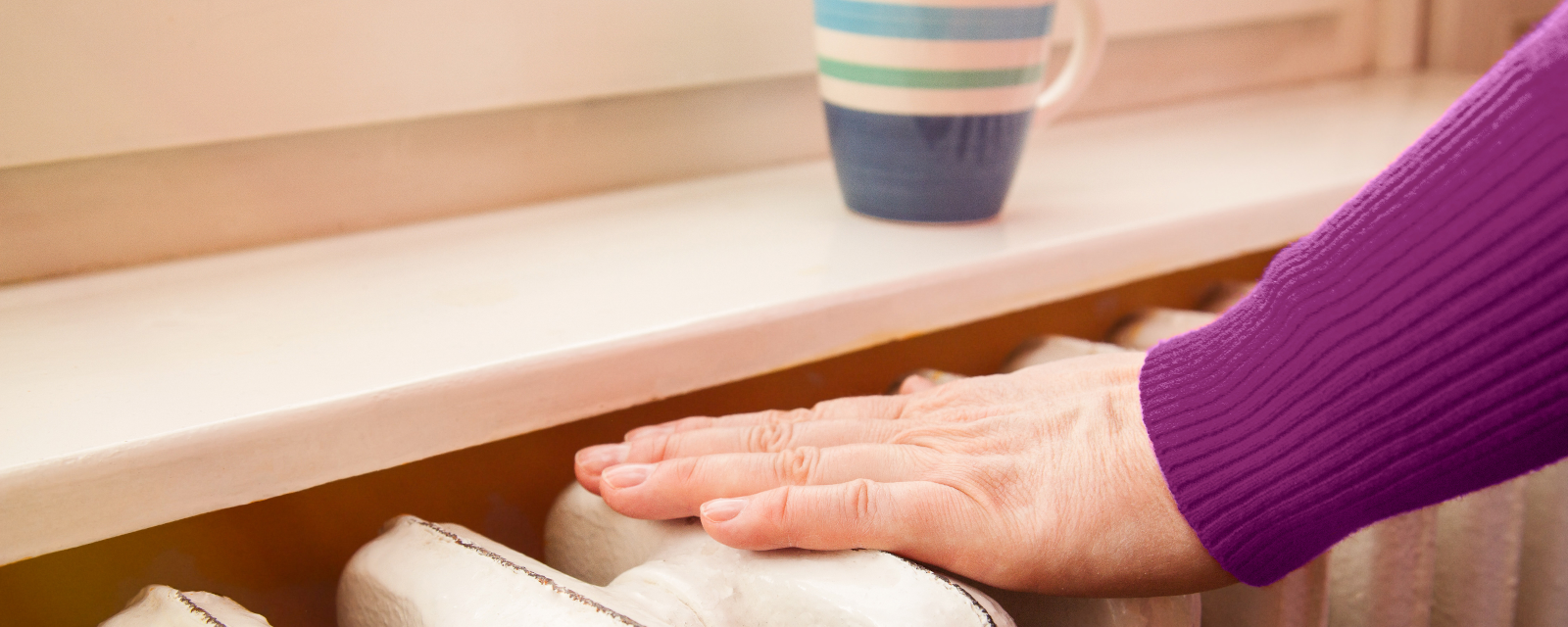 Eine Hand liegt auf dem kalten Heizkörper Eine Hand liegt auf dem kalten Heizkörper