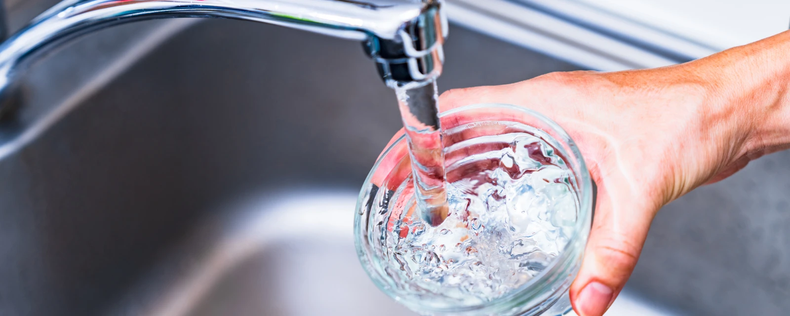 Eine Person füllt ein Glas mit Leitungswasser.