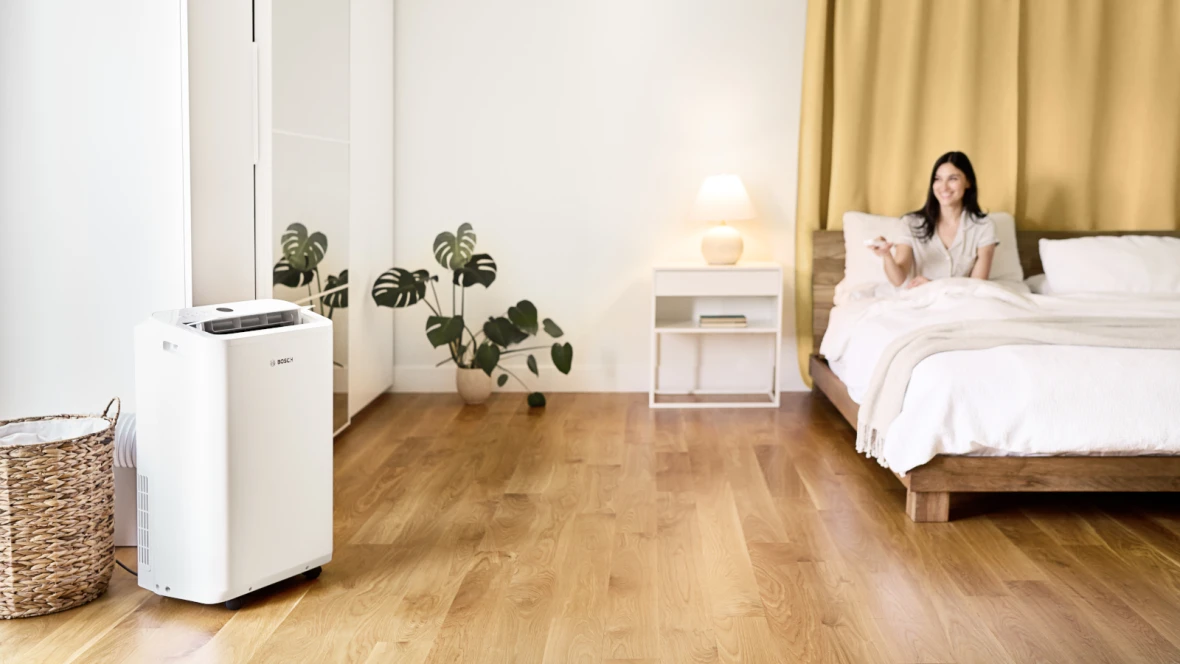 Cool 2000 steht im Schlafzimmer, während Frau im Bett liegt