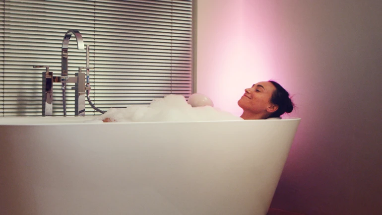 Eine Frau sitzt in der Badewanne im Bad un genießt das warme Wasser.