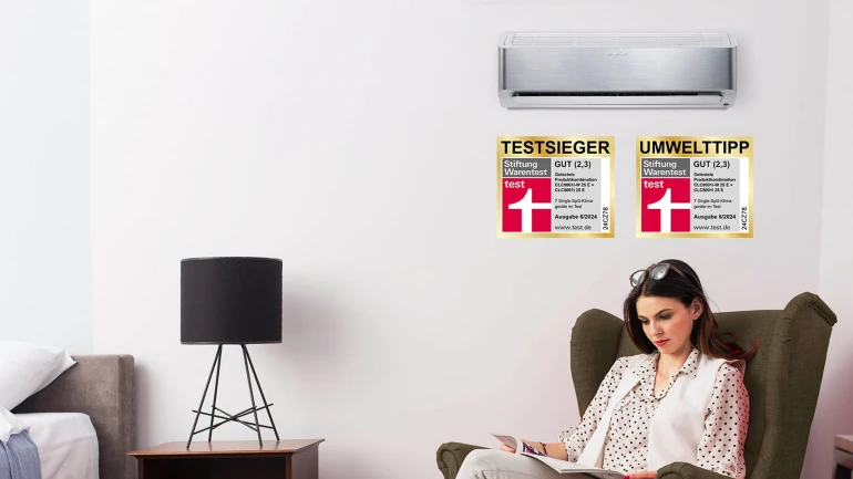 Climate Class 8000i an der Wand im Wohnzimmer montiert, daneben eine Frau im Sessel, die liest.