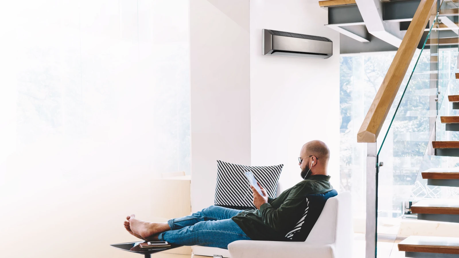 Ein Mann entspannt in seinem Sessel und genießt den komfortablen, energiesparenden Betrieb dank modernster Inverter-Technologie. Das ist der Climate Class 8000i.