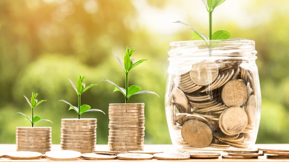 Türme aus Münzen und Glas voll mit Münzen in einer Reihe stehend