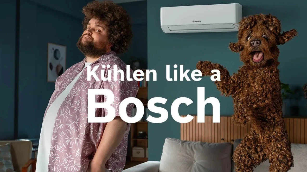 Ein Mann und sein Hund befinden sich im Schlafzimmer. Im Hintergrund ist die Bosch Climate Class 8000i zu sehen. Zudem ist das Testsieger Logo von Stiftung Warentest abgebildet.