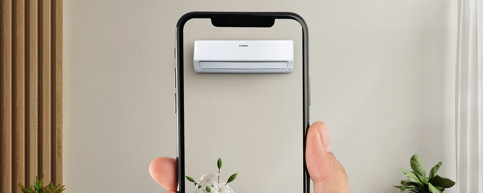 Hånd, der holder en smartphone med en virtuel visning af et klimaanlæg.