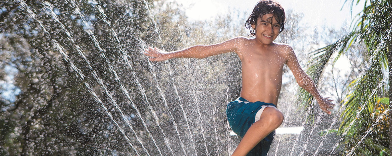 Niño jugando con agua en el jardín Niño jugando con agua en el jardín