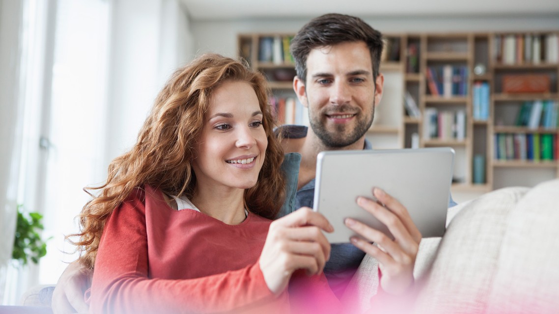 A young couple checks the COP of their heat pump on a tablet.