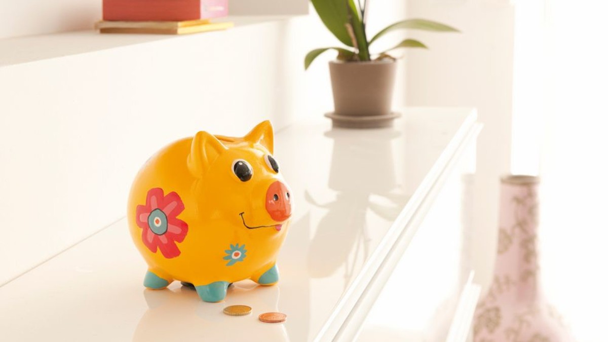 Yellow piggy bank with some coins lying on the table.