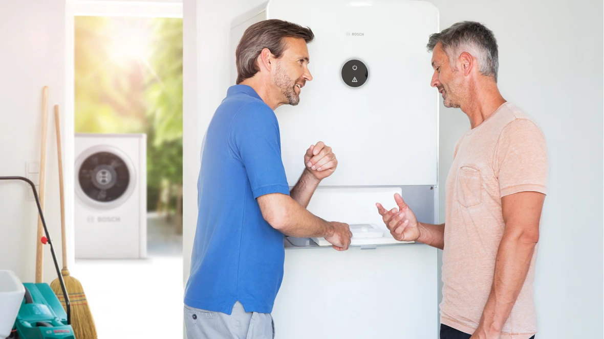 Deux hommes discutent devant une pompe à chaleur air-eau