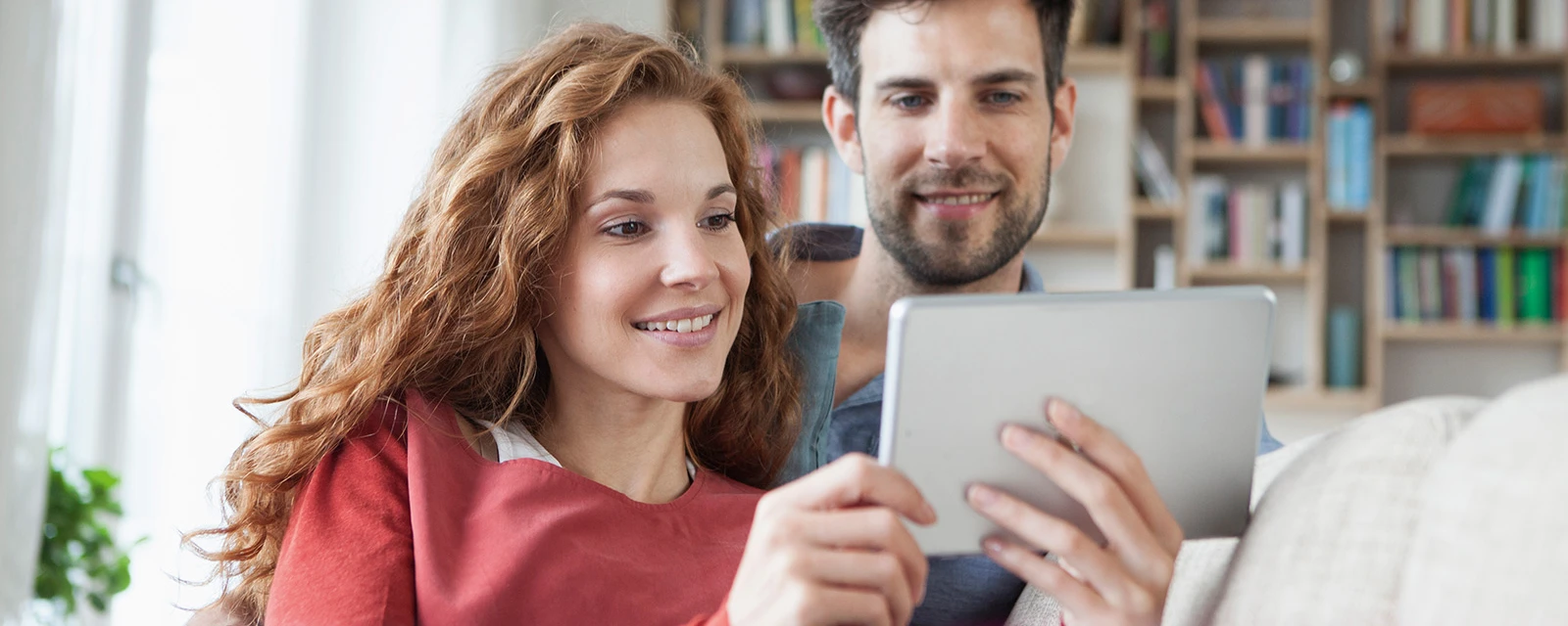 Un jeune couple vérifie sur une tablette le coefficient de performance annuel de sa pompe à chaleur.