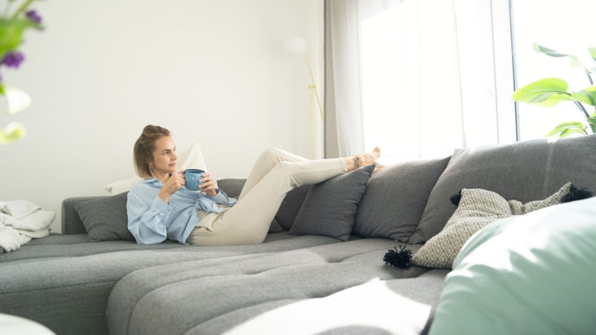 Une femme se détend sur le canapé et apprécie l'appartement frais.