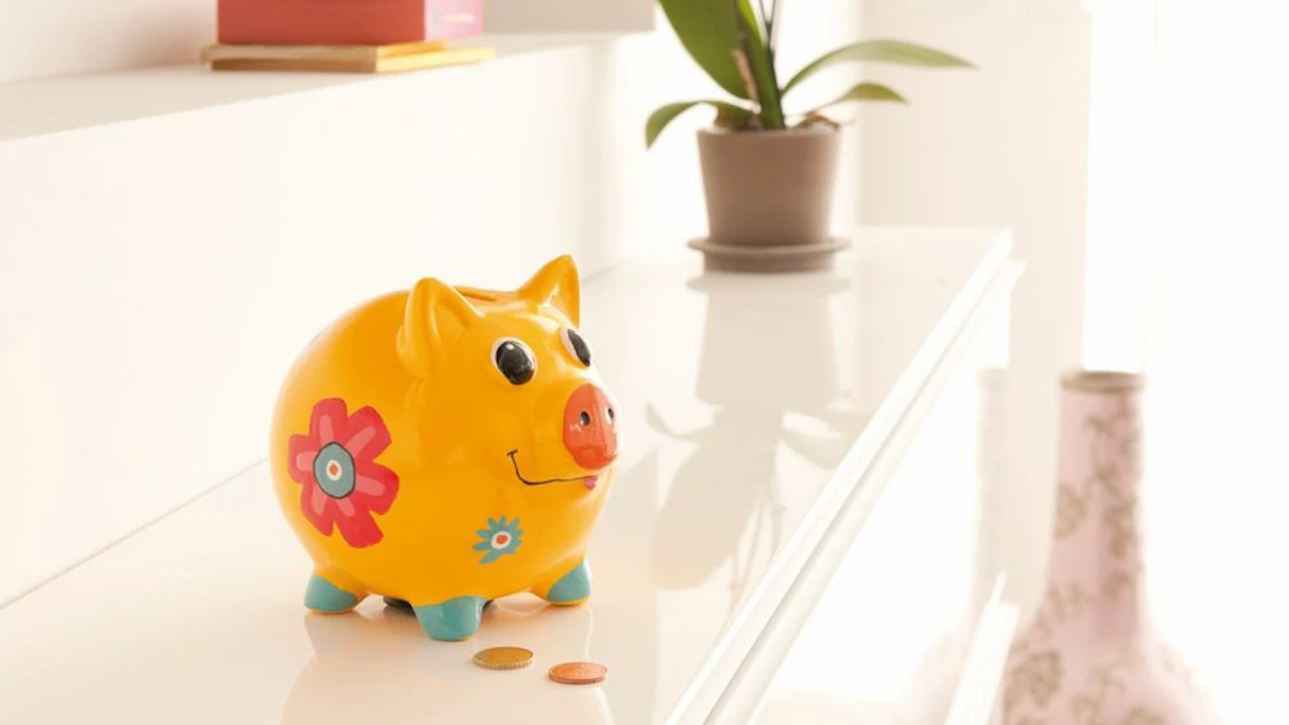 Tirelire jaune avec quelques pièces de monnaie posées sur la table.