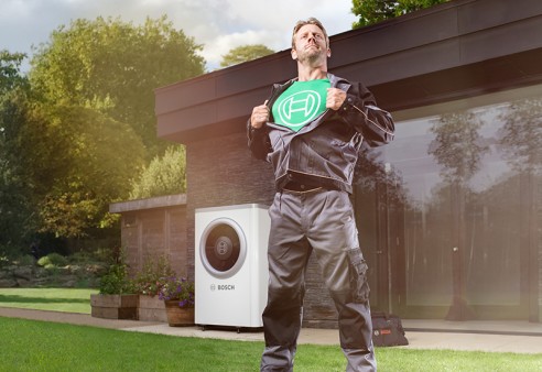 Un installateur devant une pompe à chaleur Bosch dans un jardin