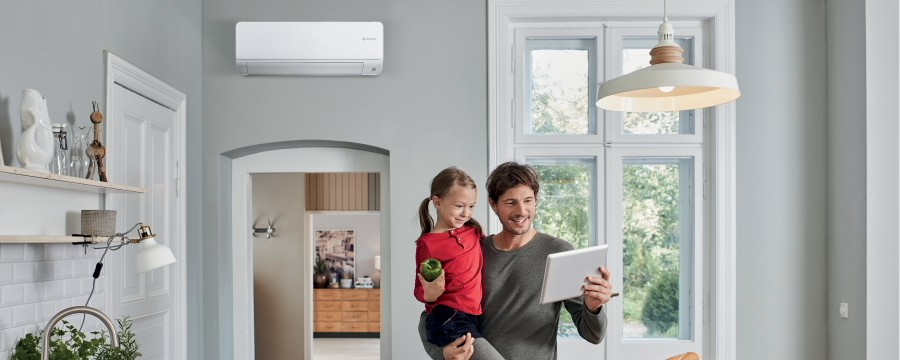 Père avec son enfant regardant une tablette avec une climatisation Bosch Père avec son enfant regardant une tablette avec une climatisation Bosch
