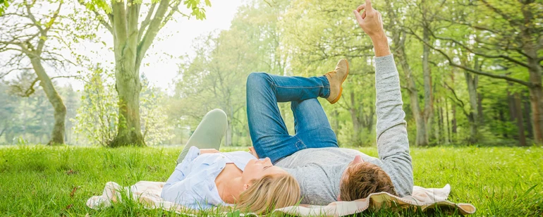 A couple is lying on a meadow.