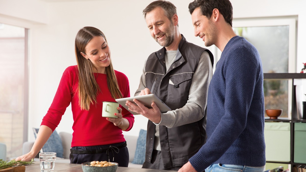 Couple has heating engineer show them the geothermal heat pump on a tablet Couple has heating engineer show them the geothermal heat pump on a tablet