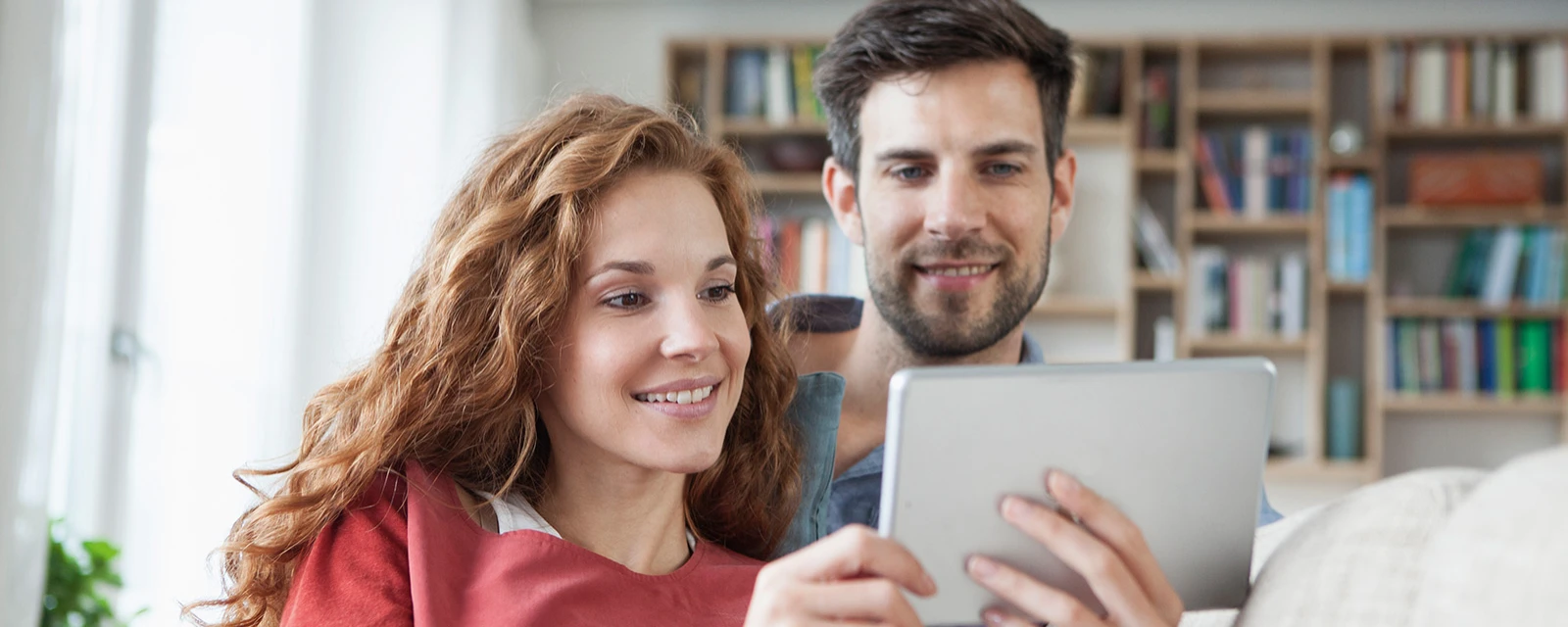 A young couple checks the COP of their heat pump on a tablet.