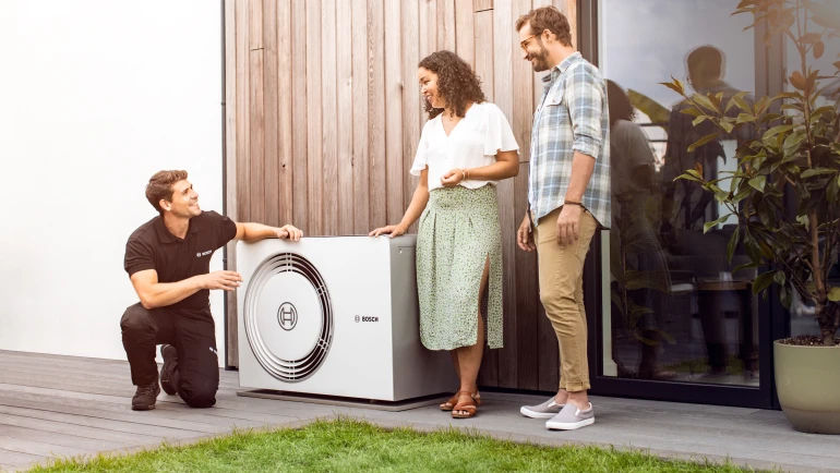 A Bosch Compress 5800 AW hőszivattyúja mellett áll egy kivitelező és egy pár