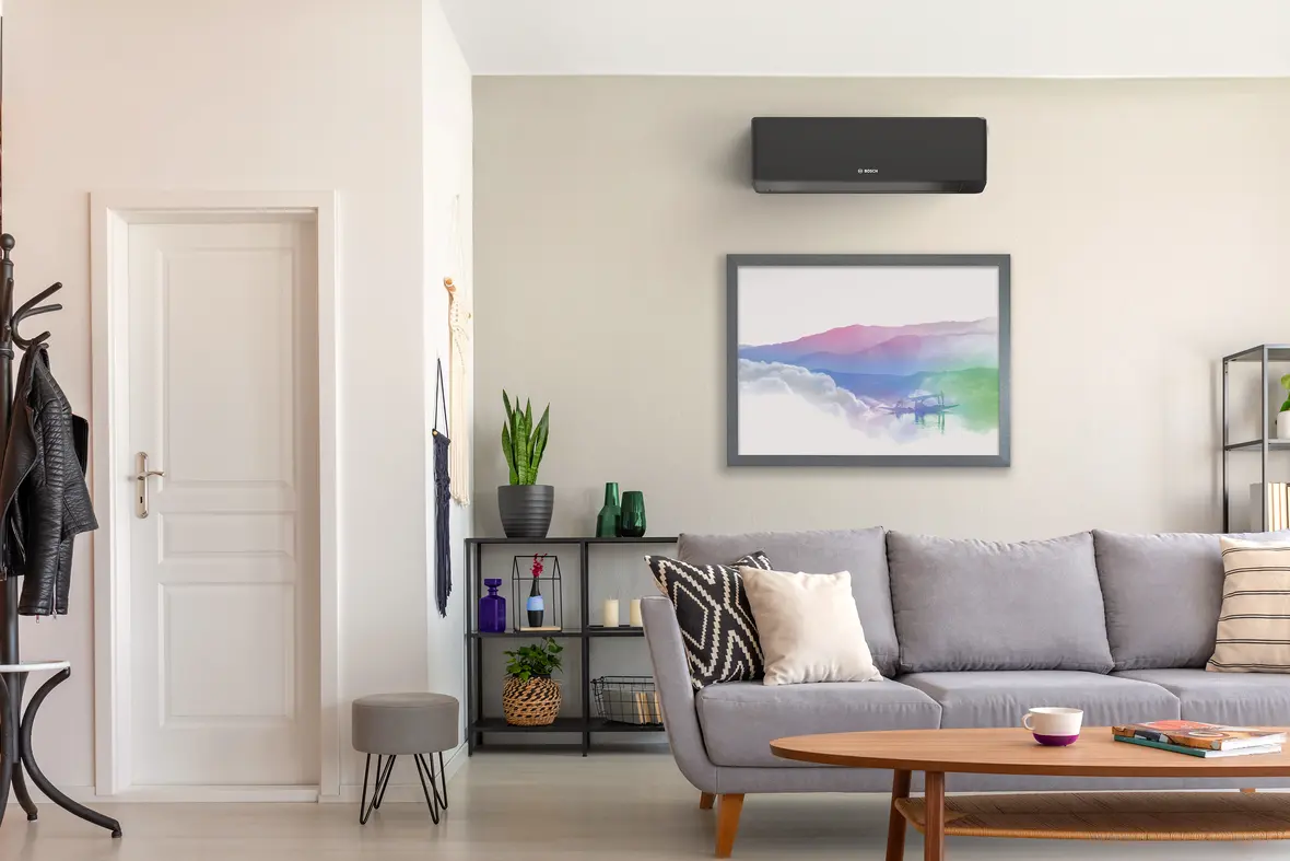 Modernes Wohnzimmer mit wandmontierter Bosch Climate 7000i Single-Split Klimagerät über einem gerahmten Bild
