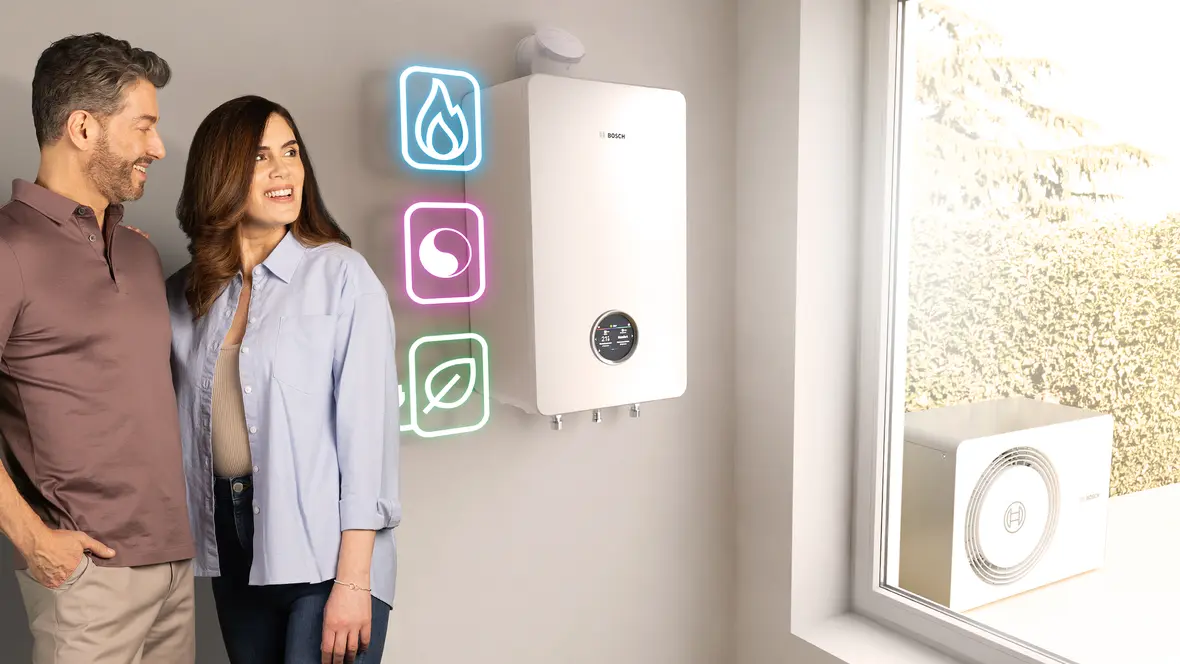 Paar steht vor Bosch All-in-One Heizung Compress Hybrid 5800i G, Icons für Gas, Hybrid und Wärmepumpe leuchten daneben.