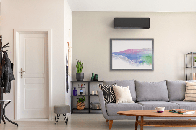 Modernes Wohnzimmer mit wandmontierter Bosch Climate 7000i Single-Split Klimagerät über einem gerahmten Bild