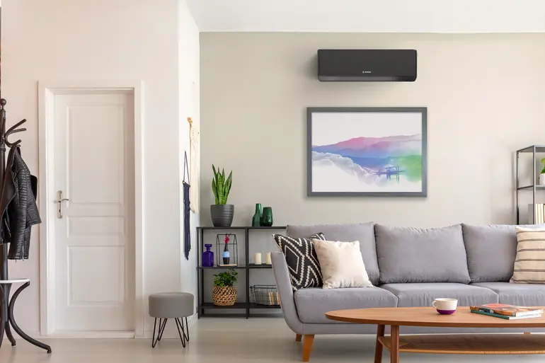 Modernes Wohnzimmer mit wandmontierter Bosch Climate 7000i Single-Split Klimagerät über einem gerahmten Bild