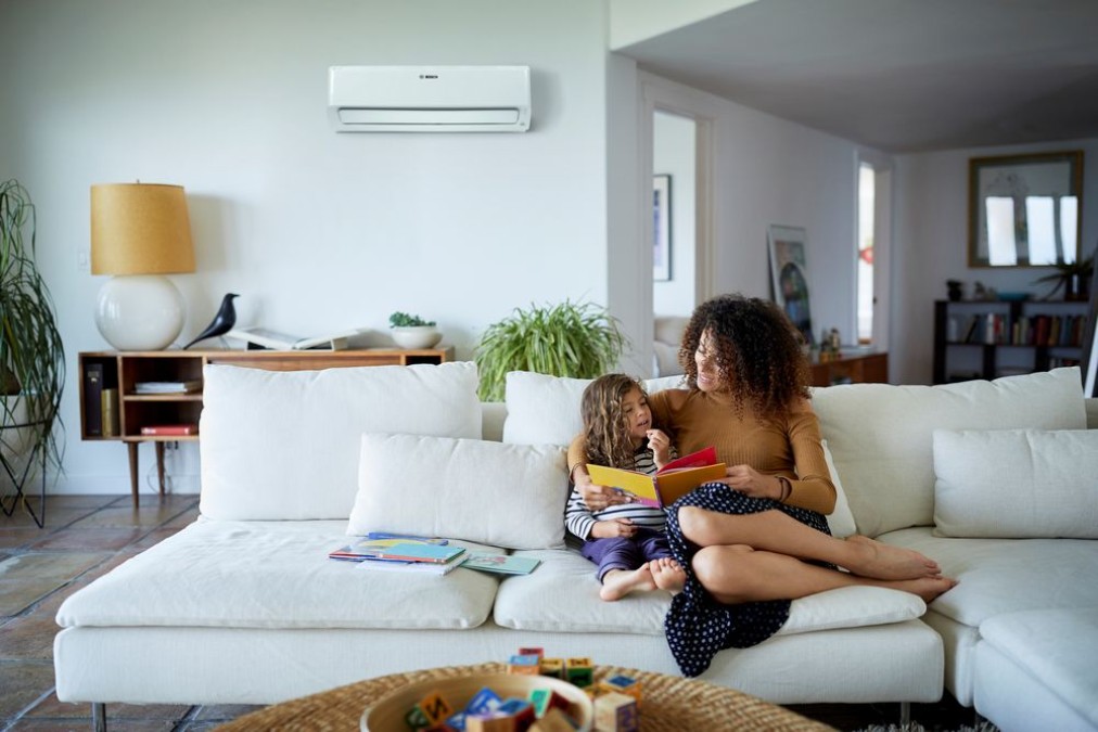 Climate Class 6000i in the apartment mounted on the wall behind the sofa, on the sofa sits a mother with her child.