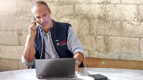 Bosch zaposleni u korisničkoj službi razgovara telefonom i gleda u laptop