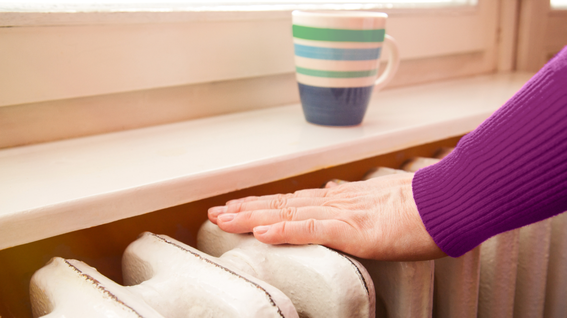 A woman puts her hand on a radiator. A woman puts her hand on a radiator.