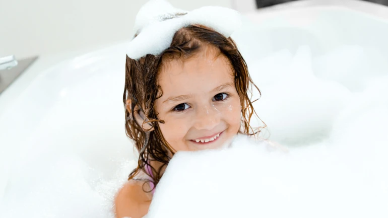 Kid playing in a bath tub with foam