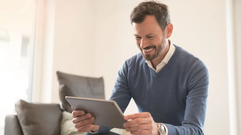 Laughing man looks at his tablet