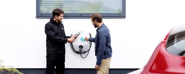 Zákazník a montážnik stojaci s RFID kartou pred nabíjacou stanicou - wallboxom Bosch Zákazník a montážnik stojaci s RFID kartou pred nabíjacou stanicou - wallboxom Bosch