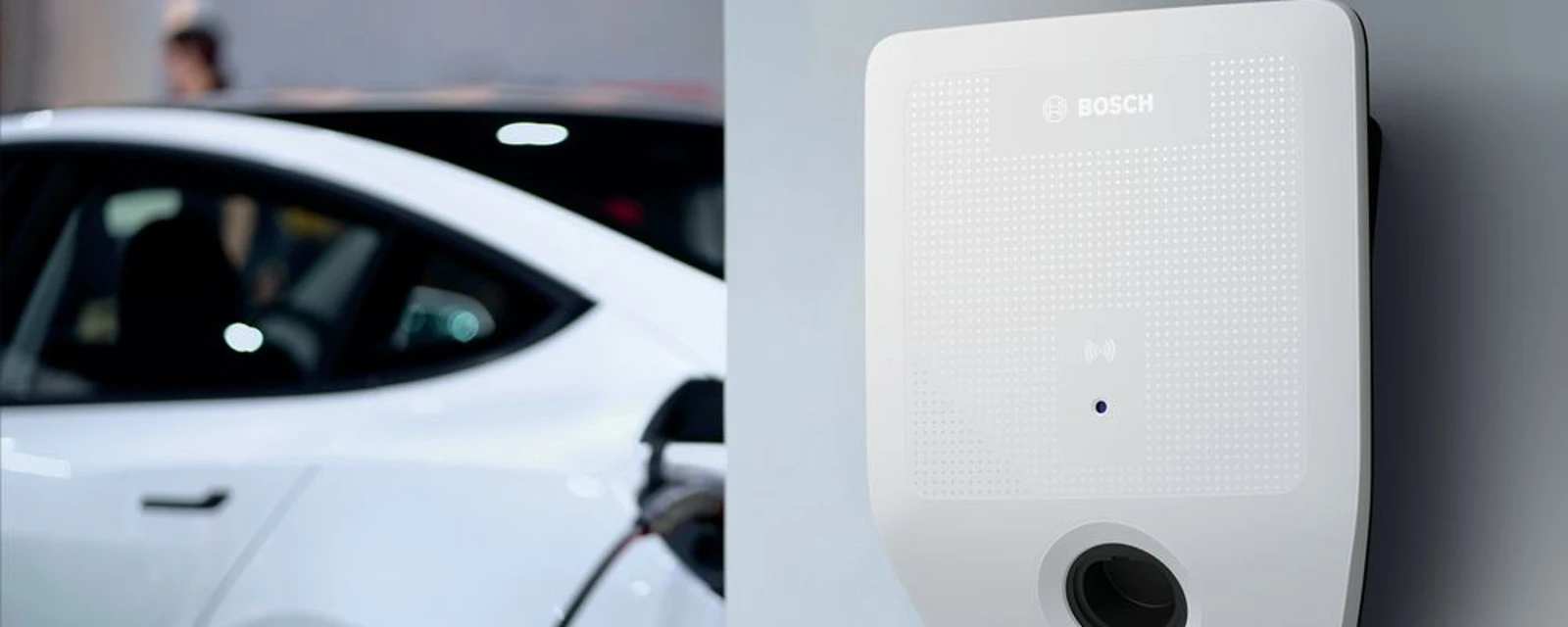 Detail wallboxu Bosch, nabíjajúce sa biele auto v pozadí