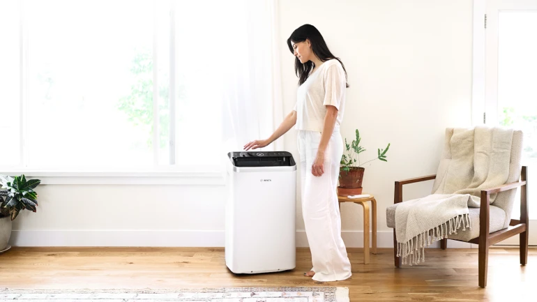 Woman stands in the living area and operates Cool 4000 on the display