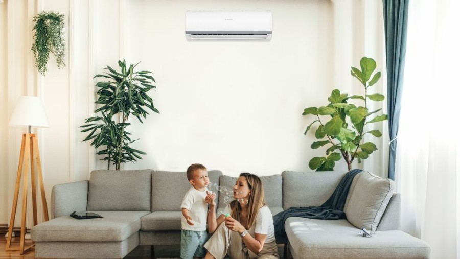 На стіні кондиціонер Bosch Climate, біля дивану жінка з дитиною