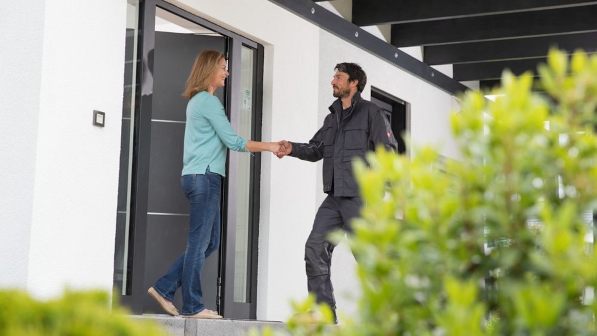 Сантехнік Bosch тисне руку жінці біля під'їзду будинку Сантехнік Bosch тисне руку жінці біля під'їзду будинку