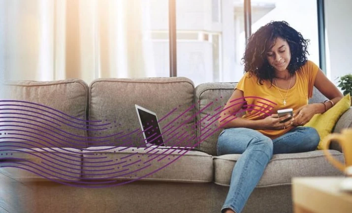 Woman sitting on couch with phone and computer.