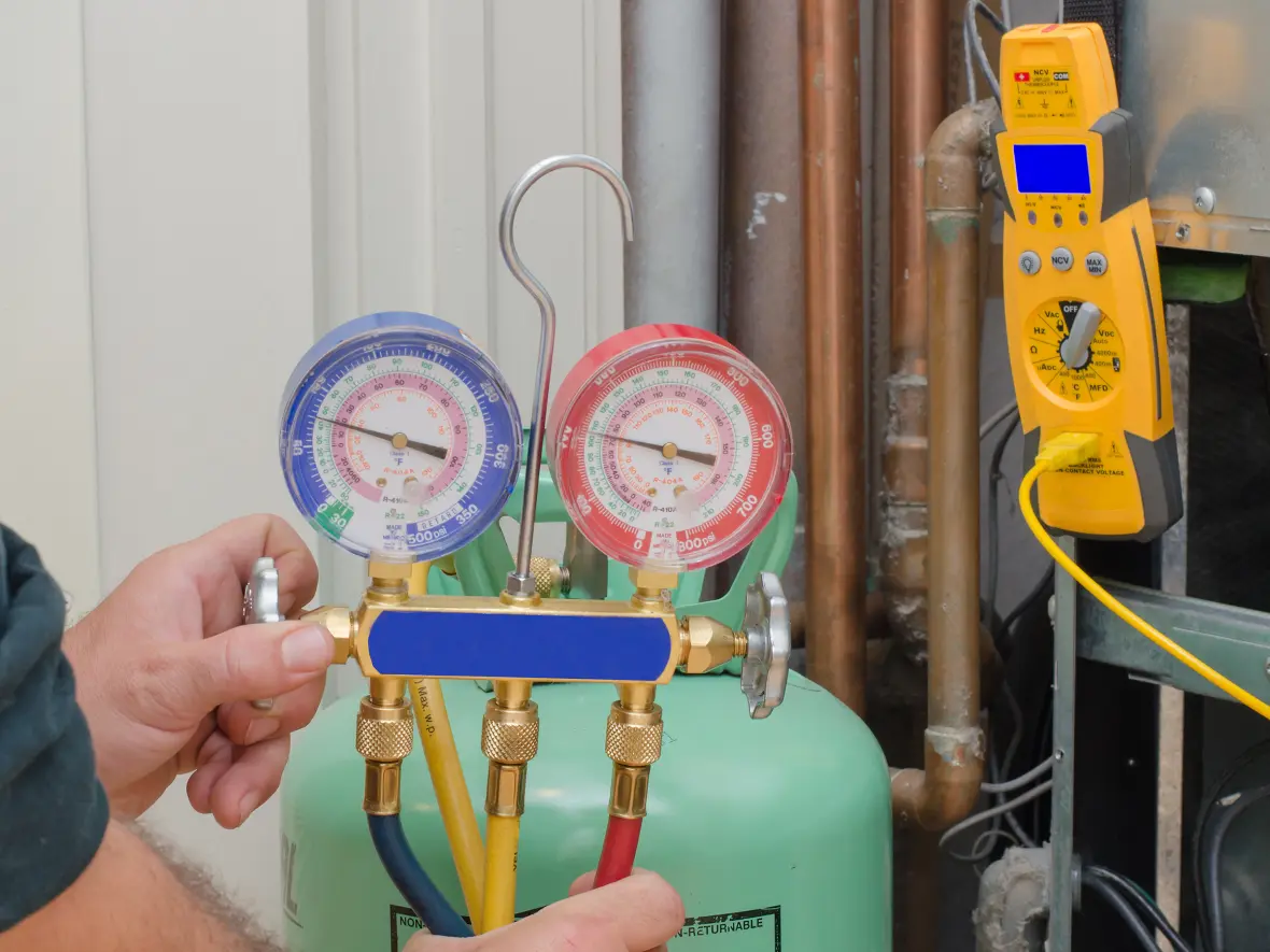 An HVAC contractor holding a refrigerant gauge